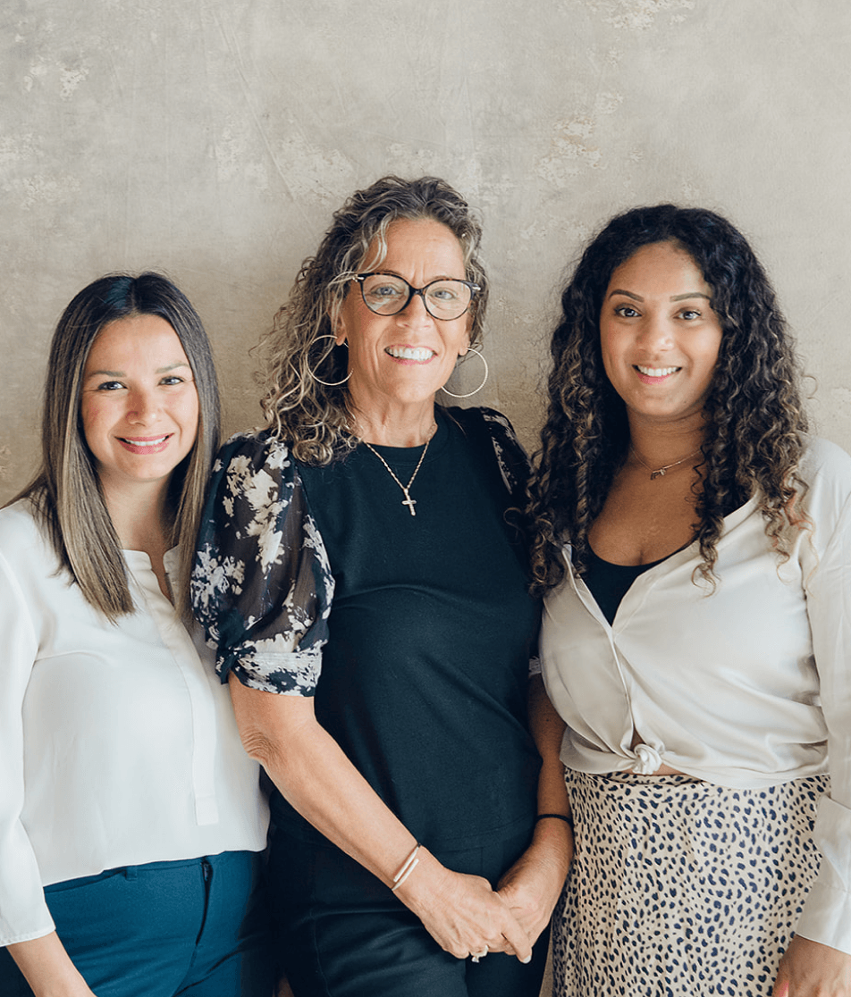 Professional photo of three women in front of a neutral backdrop smiling